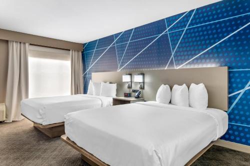 two beds in a hotel room with blue wall at Comfort Inn & Suites Irving Las Colinas DFW in Irving