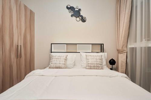 a bedroom with a bed with white sheets and pillows at Cosy 1 Bedroom in Damac Hills | OFEX in Dubai