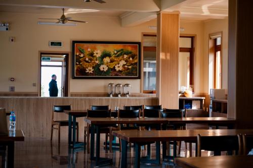 a restaurant with tables and chairs and a painting on the wall at Bavieco - Nghỉ dưỡng, Dưỡng lão & Chữa bệnh theo Đông y in Ba Vì