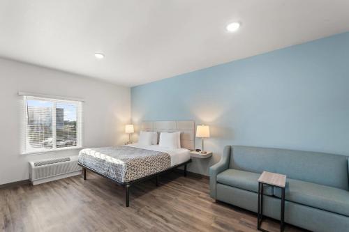 a bedroom with a bed and a blue couch at WoodSpring Suites Jackson Pearl I-20 in Pearl