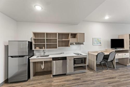 a kitchen with a refrigerator and a table and chairs at WoodSpring Suites Jackson Pearl I-20 in Pearl
