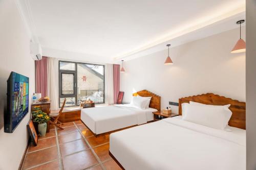 a hotel room with two beds and a window at 赛家花园酒店SAI JIA Garden HOTEL in Dali Ancient Town