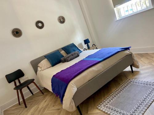 a bedroom with a large bed with blue and purple sheets at Dalston Luxe Studios, 10 minutes away from Liverpool Train Station in London