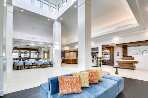 a living room with a blue couch and tables at Hilton Garden Inn Louisville Airport in Louisville