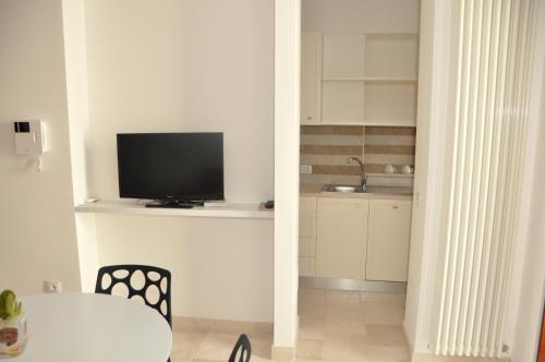 a living room with a tv and a table and a kitchen at Porta Barsento in Putignano