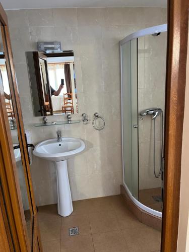a bathroom with a sink and a shower with a mirror at Pensiunea Aries Arieseni in Arieşeni