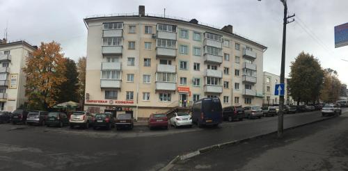 a large building with cars parked in a parking lot at City Centre Apartment on Krylenko 7 in Mogilev