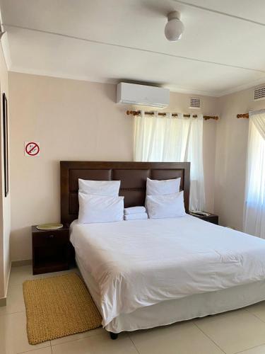 a bedroom with a large bed with white sheets and pillows at Emangunini Guest house in Richards Bay