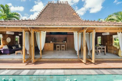 a pavilion with a pool in front of a house at Villa Lucky in Canggu