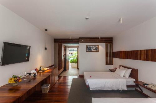 a bedroom with a bed and a flat screen tv at Hotel Somadevi Angkor Boutique and Resort in Siem Reap