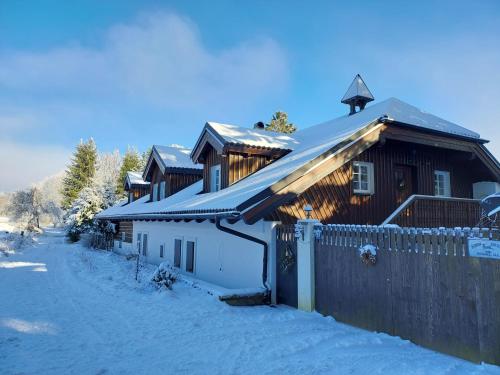 a house in the snow with a fence at Apartmány U Šakala in Zdíkov