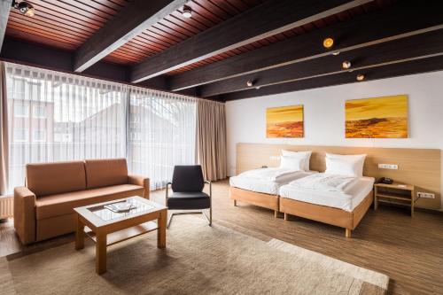 a bedroom with a bed and a couch and a table at Best Western Hotel Heide in Oldenburg
