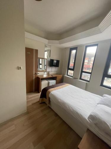 a bedroom with a bed and a desk and windows at Ceylan otel in Suşehri