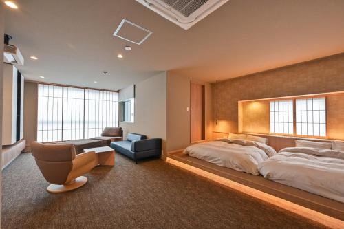 a bedroom with a large bed and a chair at Ureshino Onsen Yadoya Uchiroji in Ureshino