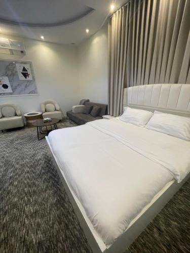 a bedroom with a large white bed and a couch at ADEL Privet Hostleإيواء خاص in Taif