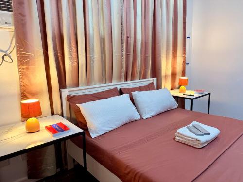 a bed with two pillows and two tables in a room at Haraya Beach House in Roxas City