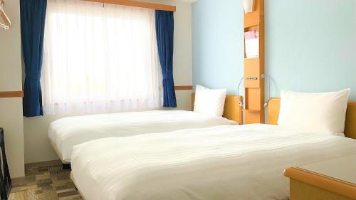 two beds in a room with a window at Toyoko Inn Fukuoka Tenjin in Fukuoka