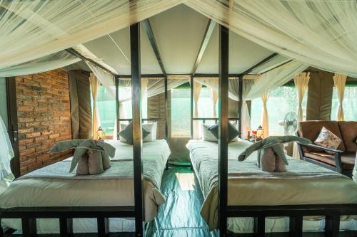 two four poster beds in a room with curtains at Sian-simba-river-lodge in Victoria Falls