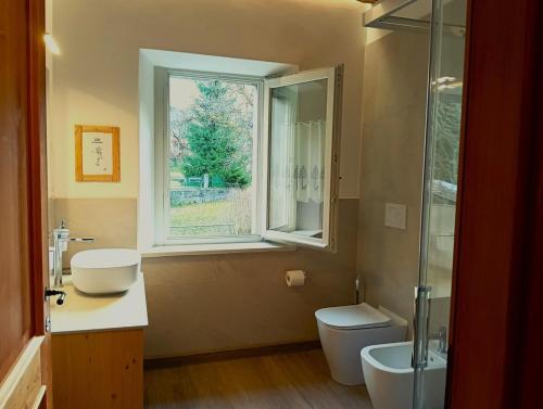 a bathroom with a toilet and a sink and a window at La Casa dei Nonni in Caralte