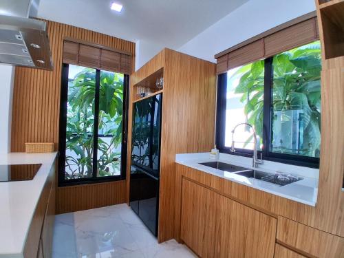 a kitchen with a sink and two large windows at Andara Ao Nang Pool Villa in Ao Nang Beach