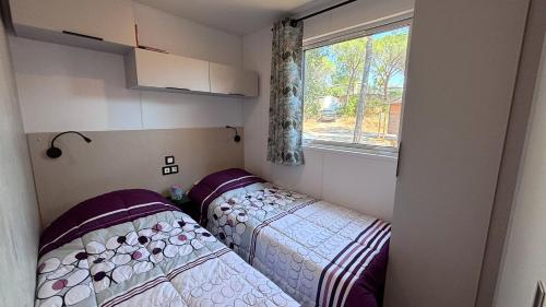 two beds in a small room with a window at Camping Les Palmiers in Hyères