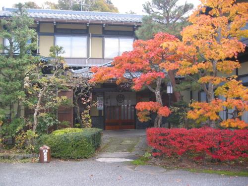 a house with colorful trees in front of it at Minshuku Iwatakan in Takayama