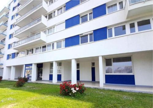 a large white building with blue doors and a yard at L'escapade Sweet home - vue sur Mer et Dragon de Calais in Calais