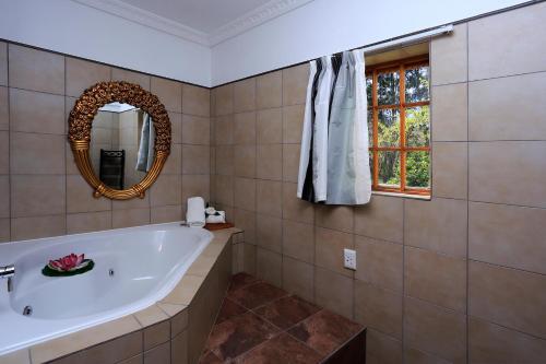 a bathroom with a tub and a mirror at Orange-Ville Lodge & Guesthouse in Stellenbosch