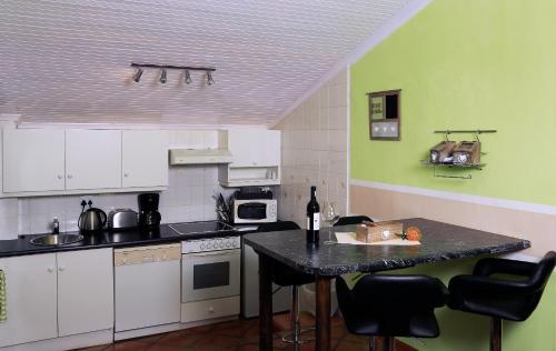 a kitchen with white cabinets and a table with chairs at Orange-Ville Lodge & Guesthouse in Stellenbosch
