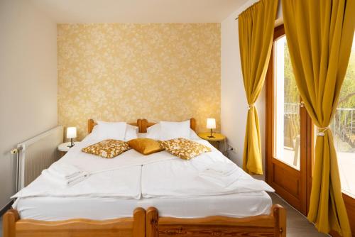 a bedroom with a bed with yellow curtains and a window at Sipos Borház és Vendégház in Badacsonyörs