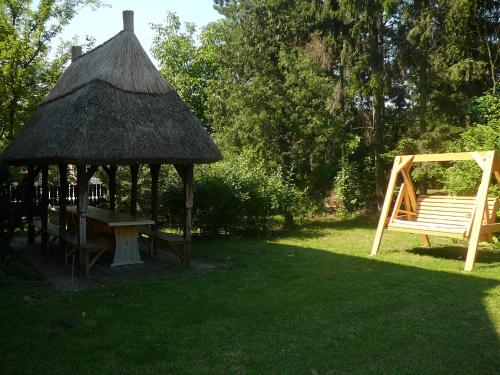 a wooden gazebo with a bench and a table at Porkoláb Apartmanház in Gyenesdiás
