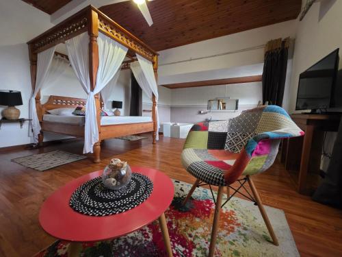 a bedroom with a bed and a table and a chair at Le Paille en Queue in Saint-Louis