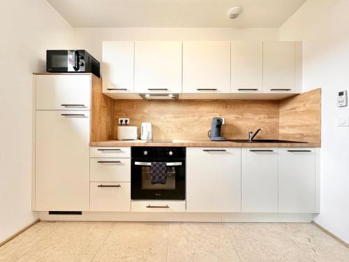 a kitchen with white cabinets and a black oven at Le Ronsard - Élégance - Central in Mont-de-Marsan
