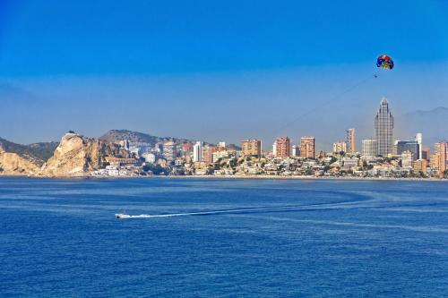 a kite flying over a body of water with a city at Irati in Benidorm
