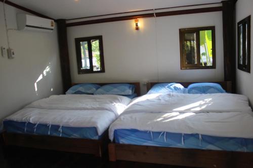 two twin beds in a room with two windows at Baan Suan La Moon in Chiang Khan