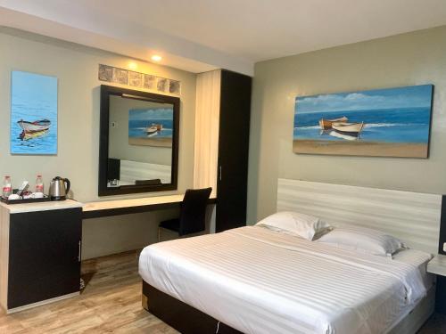 a bedroom with a bed and a desk and a mirror at Wisma Lovebird in Kalianget