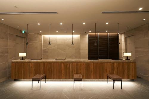 a lobby with two benches and a counter with two lights at Sotetsu Fresa Inn Ginza-Nanachome in Tokyo