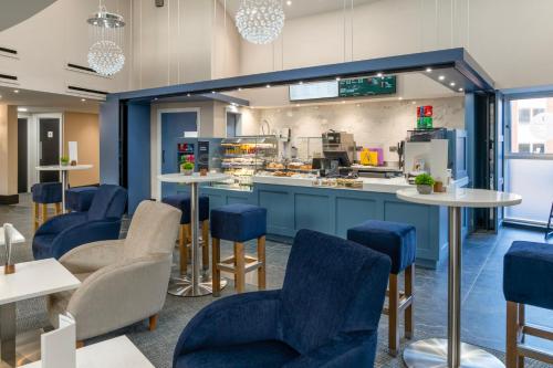 a restaurant with blue chairs and tables and a counter at Daresbury Park Hotel in Daresbury