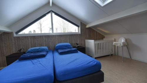 a bedroom with two blue beds and a window at Vakantiehuis Weids uitzicht nabij Tjeukemeer in Rohel