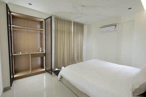a white bedroom with a bed and a closet at Supremo Home Stays in Agra
