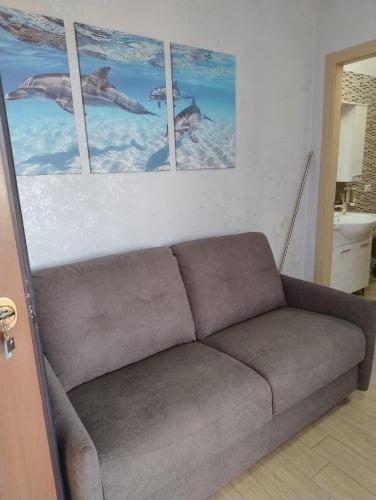 a couch in a living room with three pictures on the wall at Petit Appartament in Policoro