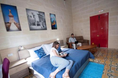 a woman sitting on a bed in a hotel room at The 1930's Maltese Residence in St Paul's Bay