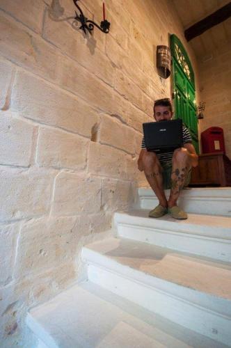 a man sitting on the stairs with a laptop at The 1930's Maltese Residence in St Paul's Bay