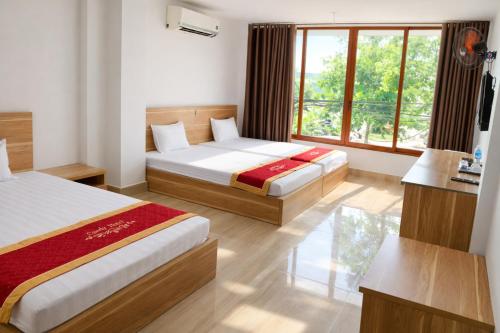 a hotel room with two beds and a window at Candy Hotel Hạ Long in Ha Long