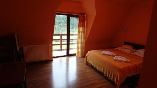 ein Schlafzimmer mit einem Bett und einem großen Fenster in der Unterkunft Pensiunea DALIA in Lepşa