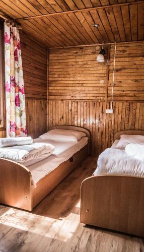 two beds in a room with wooden walls at Leśna Ryba I Domki nad jeziorem z parkiem linowym in Jedlanka Stara