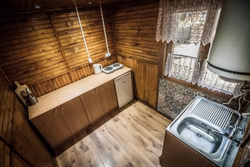 a small kitchen with a sink and a stove at Leśna Ryba I Domki nad jeziorem z parkiem linowym in Jedlanka Stara