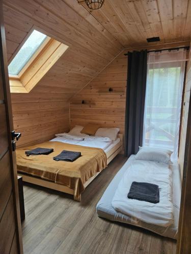 a bedroom with two beds in a wooden cabin at Domek Pod Skarpą in Wieprzec