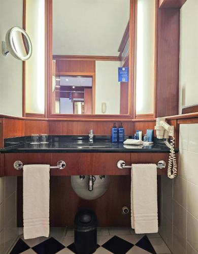 a bathroom with a sink and a mirror and towels at Radisson Blu Park Hotel & Conference Centre in Dresden