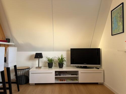 a living room with a television on a white cabinet at Top appartement in prachtige hart van Nederland Kortenhoef in Kortenhoef